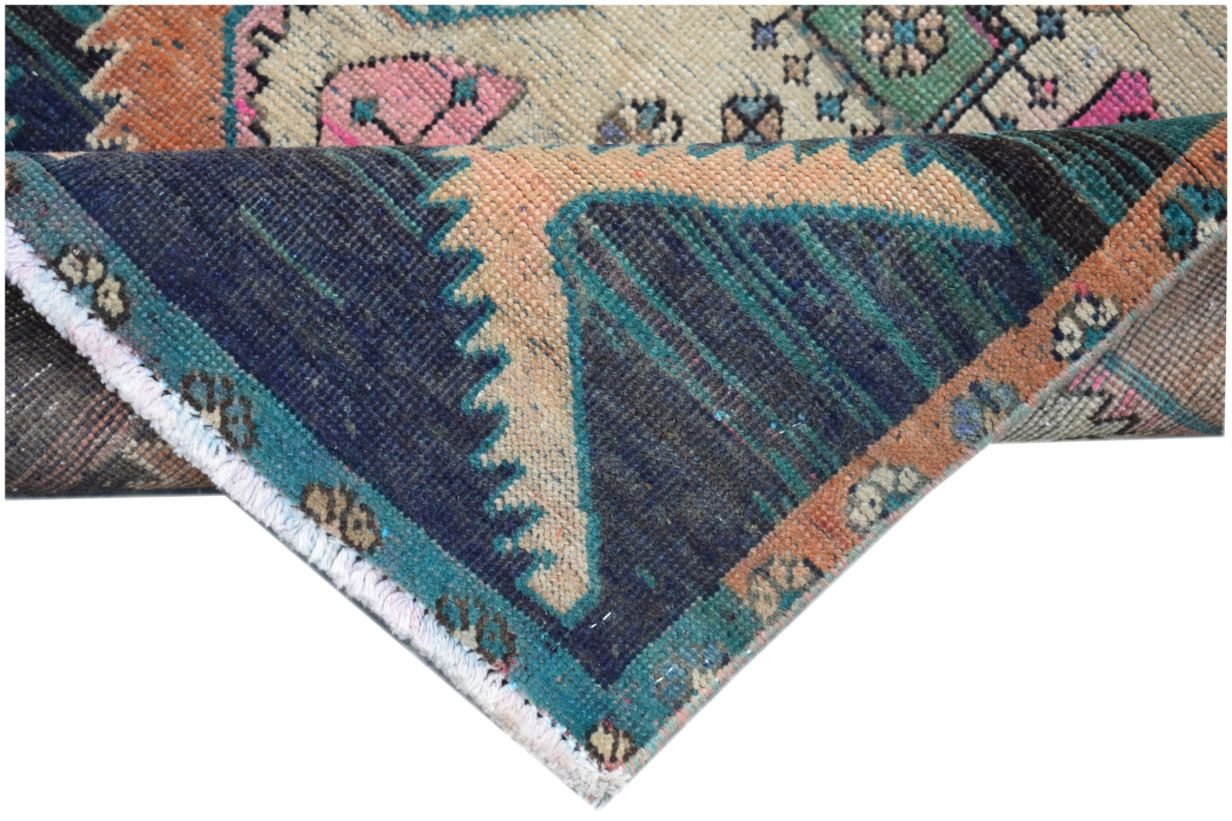 A folded vintage Persian runner featuring a geometric pattern in blue, pink, and orange tones.