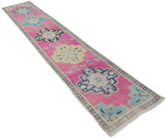A handmade vintage Persian runner rug featuring geometric medallions on a vibrant pink background.