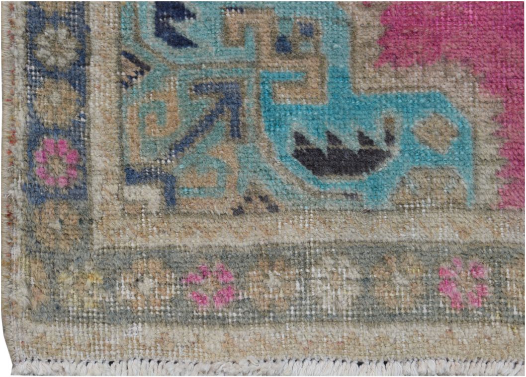 A close-up of a vintage Persian runner featuring geometric patterns in blue, pink, and beige.