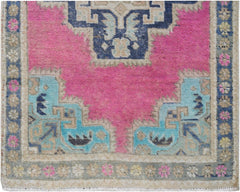A vintage Persian runner featuring a vibrant pink center with blue and beige geometric patterns.