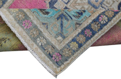 A corner of a handmade vintage Persian runner featuring a floral pattern in blue, pink, and tan.