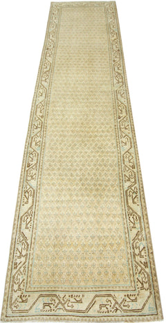 A vintage Persian runner featuring a repeating geometric pattern in beige and brown tones.