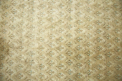 A vintage Persian runner featuring a repeating geometric pattern in muted tan and soft blue tones.