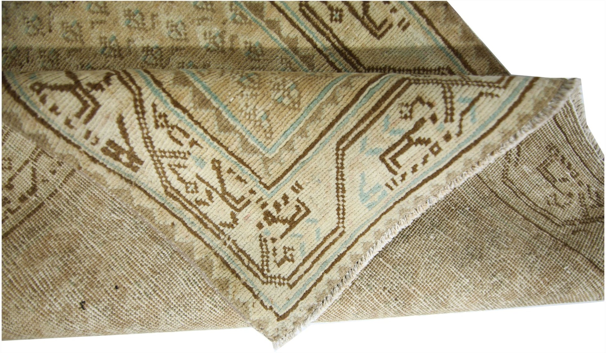 A folded vintage Persian runner featuring a geometric pattern in beige and light blue tones.