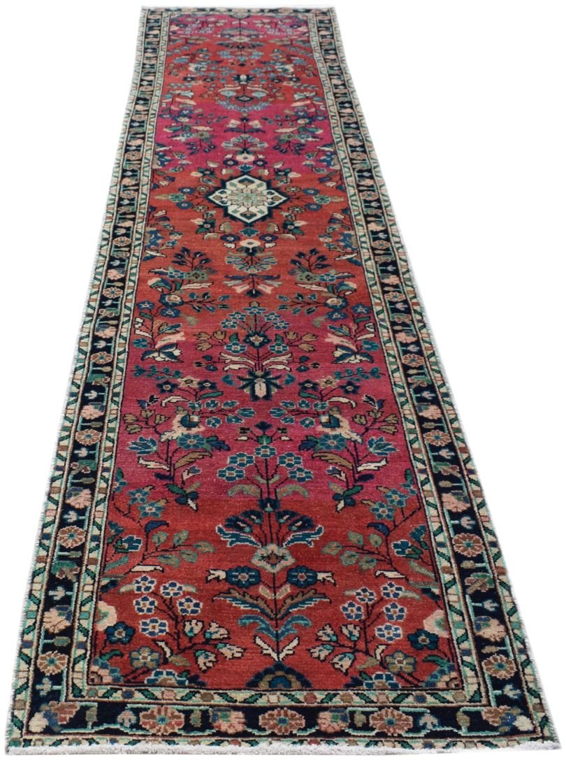A vintage Persian runner rug featuring a floral pattern in shades of red, blue, and cream.