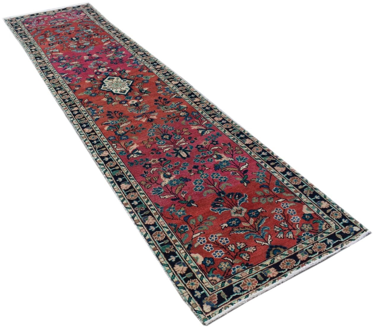 A handmade vintage Persian runner rug featuring a floral pattern on a red wool field.