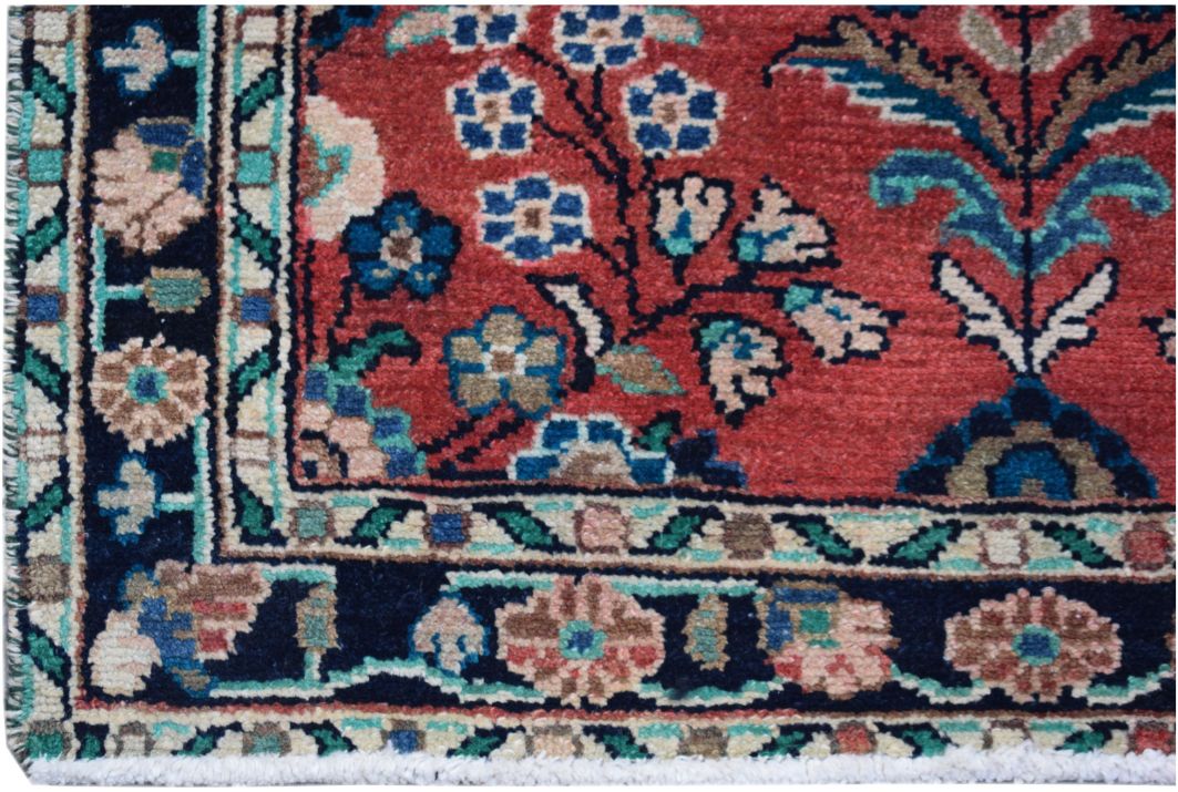 A close-up of a vintage Persian runner featuring intricate floral patterns in red and navy blue.