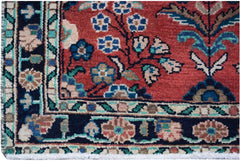 A close-up of a vintage Persian runner featuring intricate floral patterns in red and navy blue.