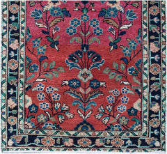 A vintage Persian runner featuring a floral pattern in shades of red, pink, and blue.