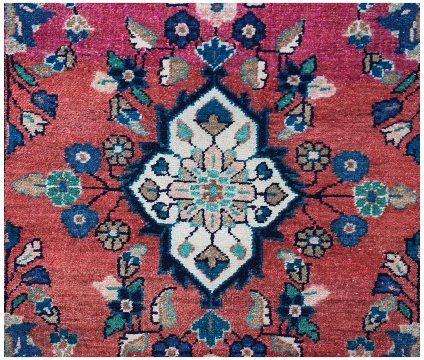 A vintage Persian runner featuring a central floral medallion on a red field with blue accents.