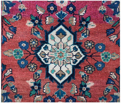 A vintage Persian runner featuring a central floral medallion on a red field with blue accents.