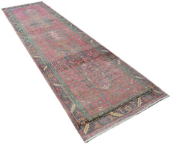 A vintage Persian runner rug featuring a faded pink field with intricate tribal patterns.