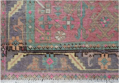 A handmade vintage Persian runner featuring a geometric tribal pattern in pink, teal, and grey.