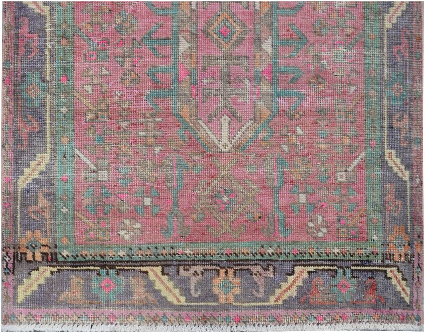 A vintage Persian runner featuring a pink field with intricate geometric patterns in teal and grey.