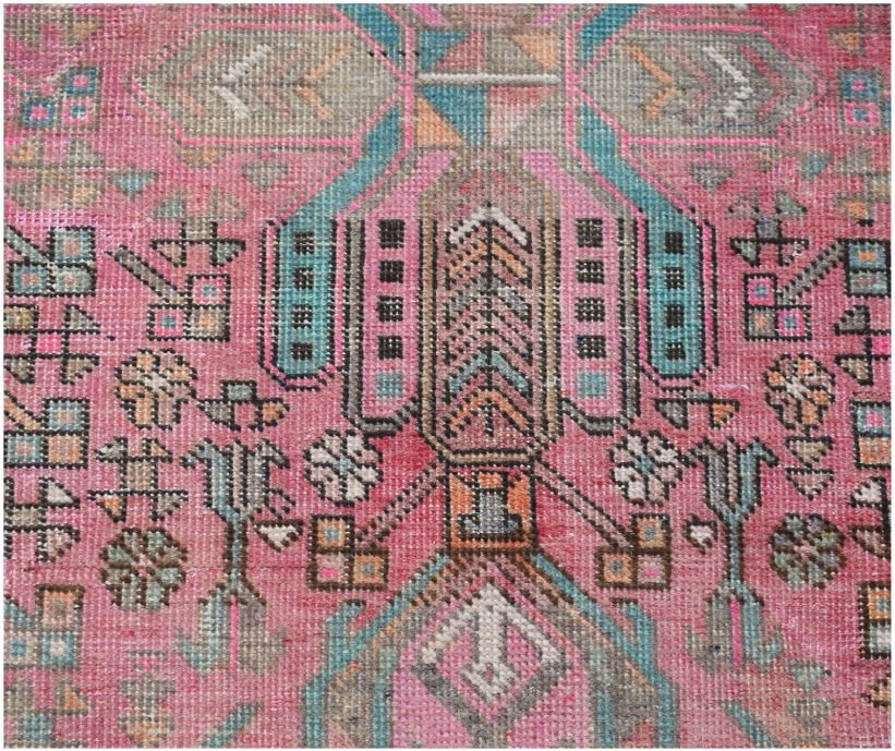 A vintage Persian runner featuring intricate tribal geometric patterns in pink, blue, and grey.