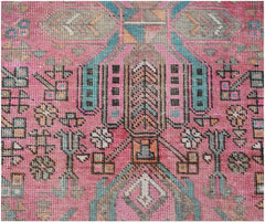 A vintage Persian runner featuring intricate tribal geometric patterns in pink, blue, and grey.