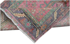 A folded vintage Persian runner featuring a vibrant pink, purple, and teal geometric pattern.