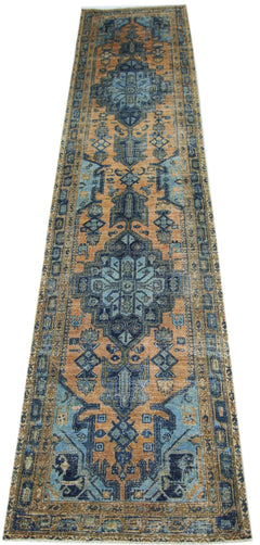 A vintage handmade Persian runner featuring a geometric floral pattern in blue and orange tones.