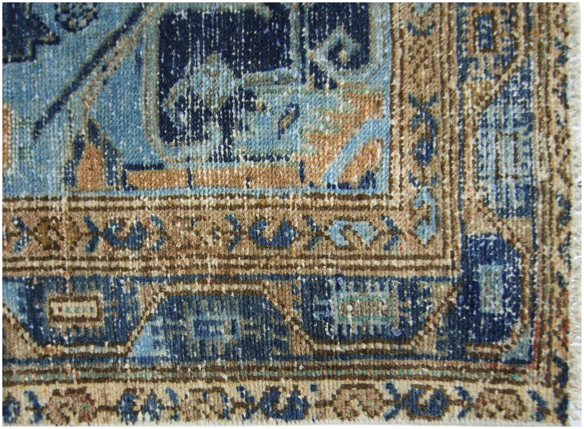 A close-up of a vintage Persian runner featuring intricate blue and tan geometric patterns.
