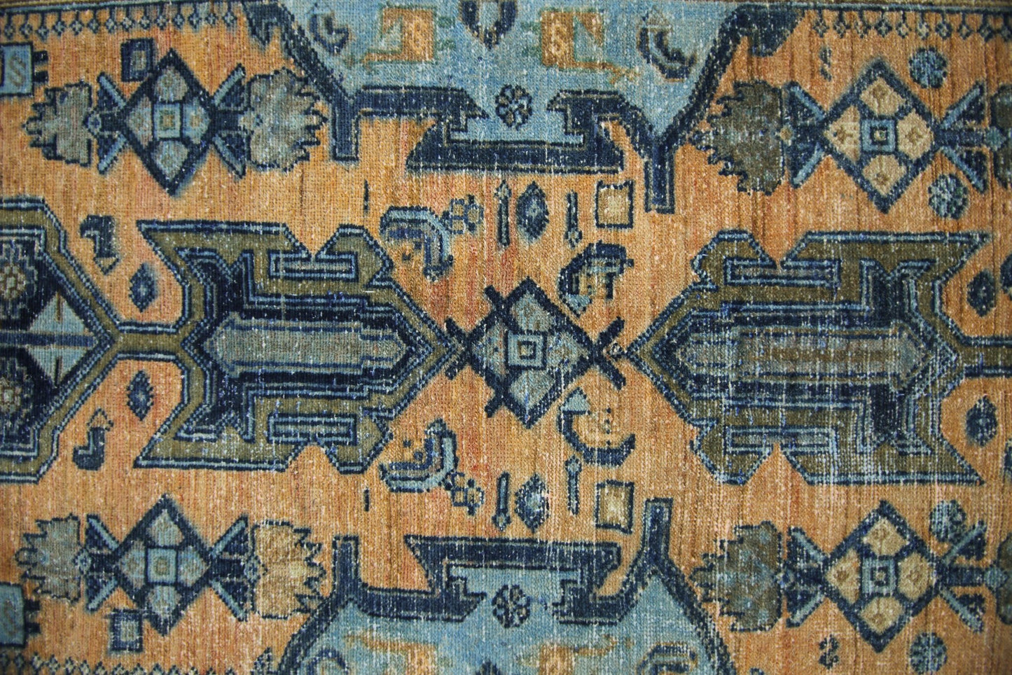A vintage Persian runner featuring geometric patterns in shades of orange, blue, and olive green.