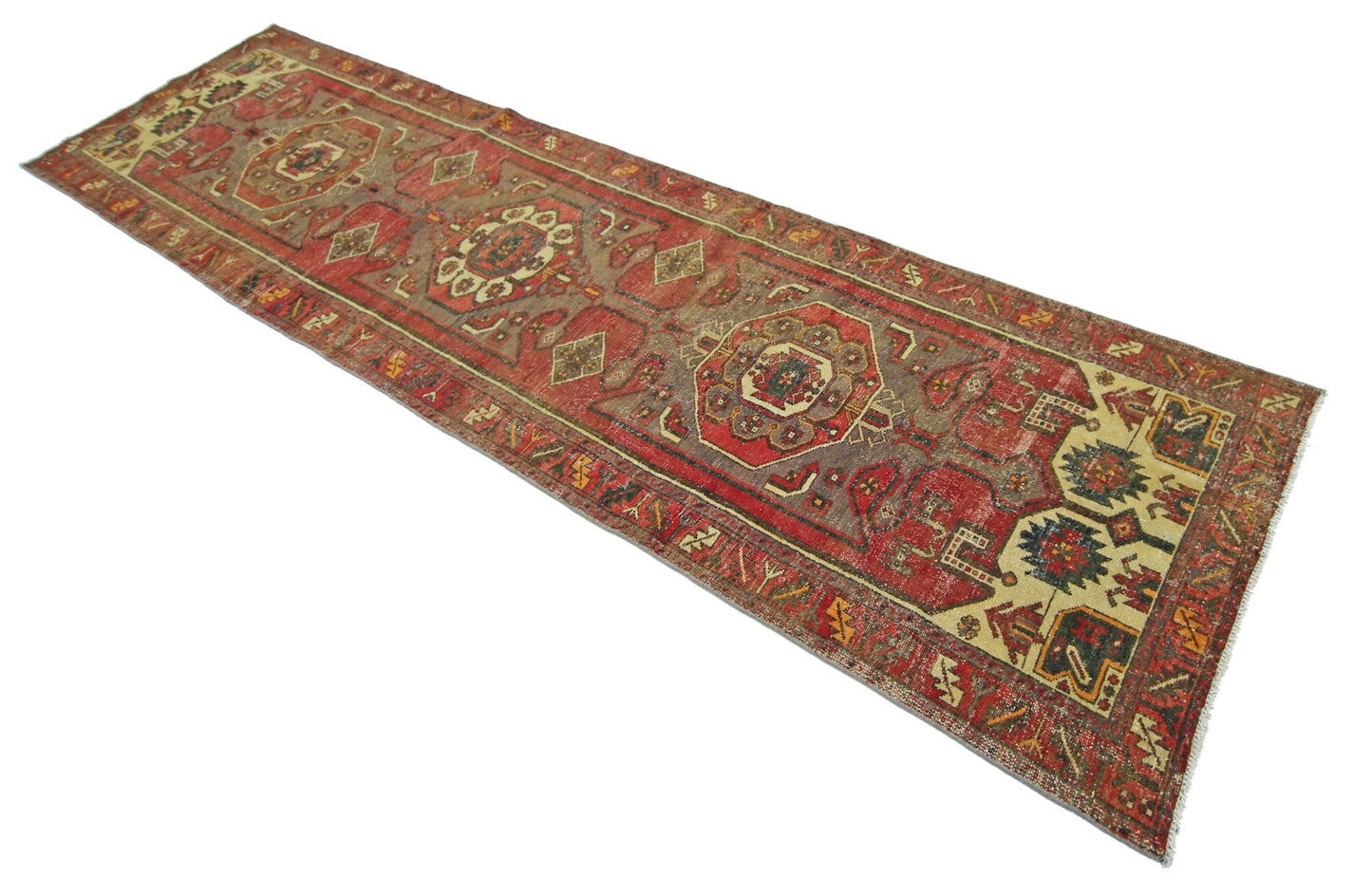 A handmade vintage Persian runner rug featuring geometric patterns in red, brown, and cream tones.