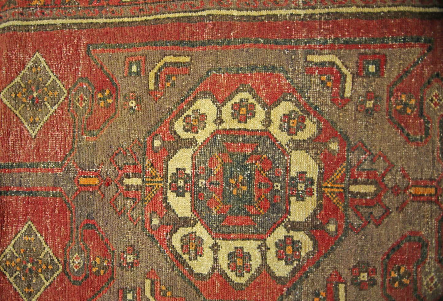 A vintage Persian runner featuring a central geometric medallion pattern in red and brown tones.