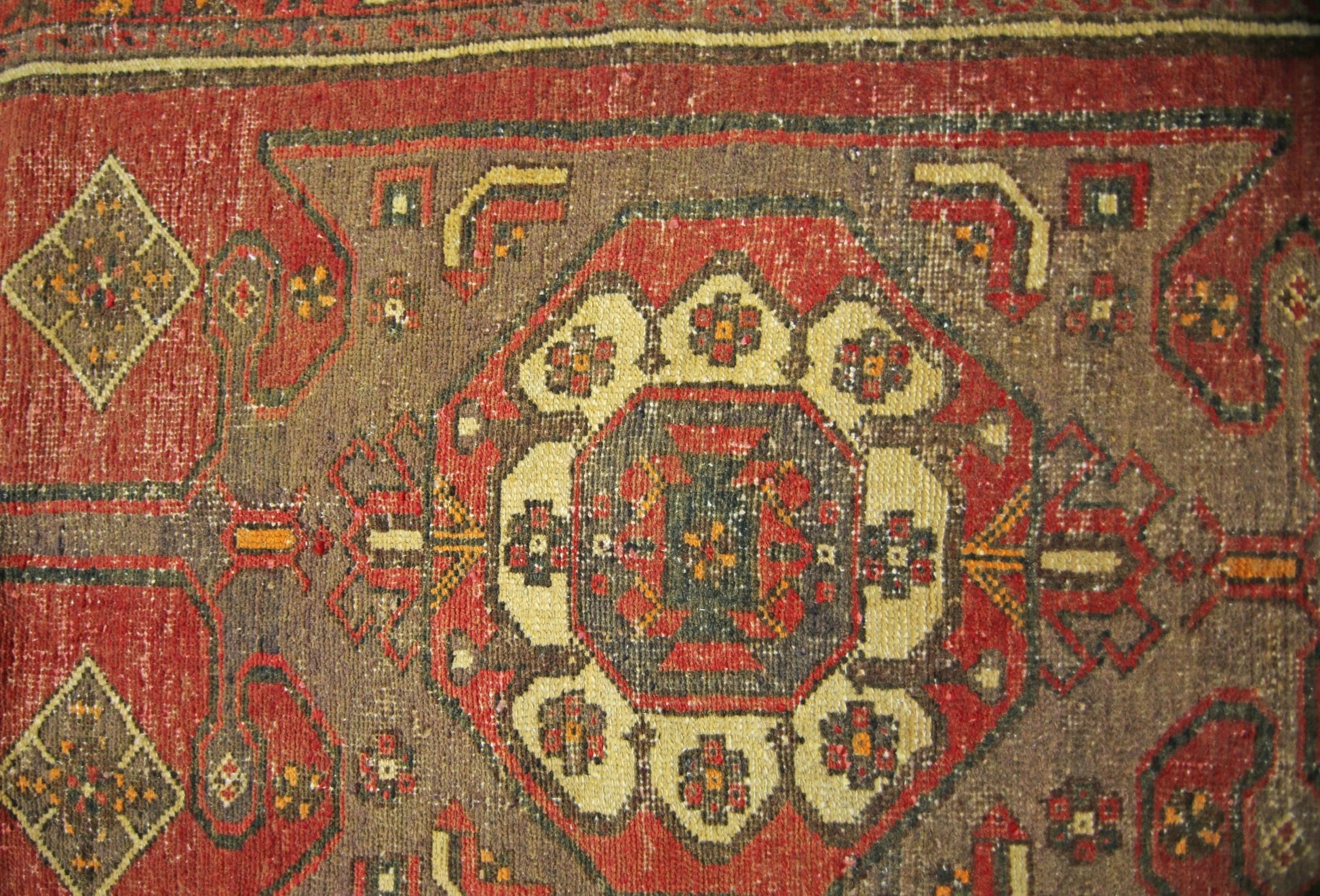 A vintage Persian runner featuring a central geometric medallion pattern in red and brown tones.