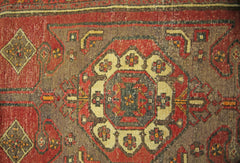 A vintage Persian runner featuring a central geometric medallion pattern in red and brown tones.