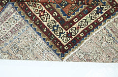 A folded vintage Persian runner featuring intricate geometric patterns in red, blue, and cream.