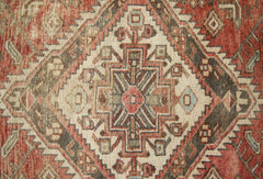 A vintage Persian runner featuring a geometric diamond medallion pattern in red, cream, and brown.