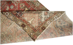 A vintage Persian runner with a folded corner revealing intricate geometric patterns and warm tones.