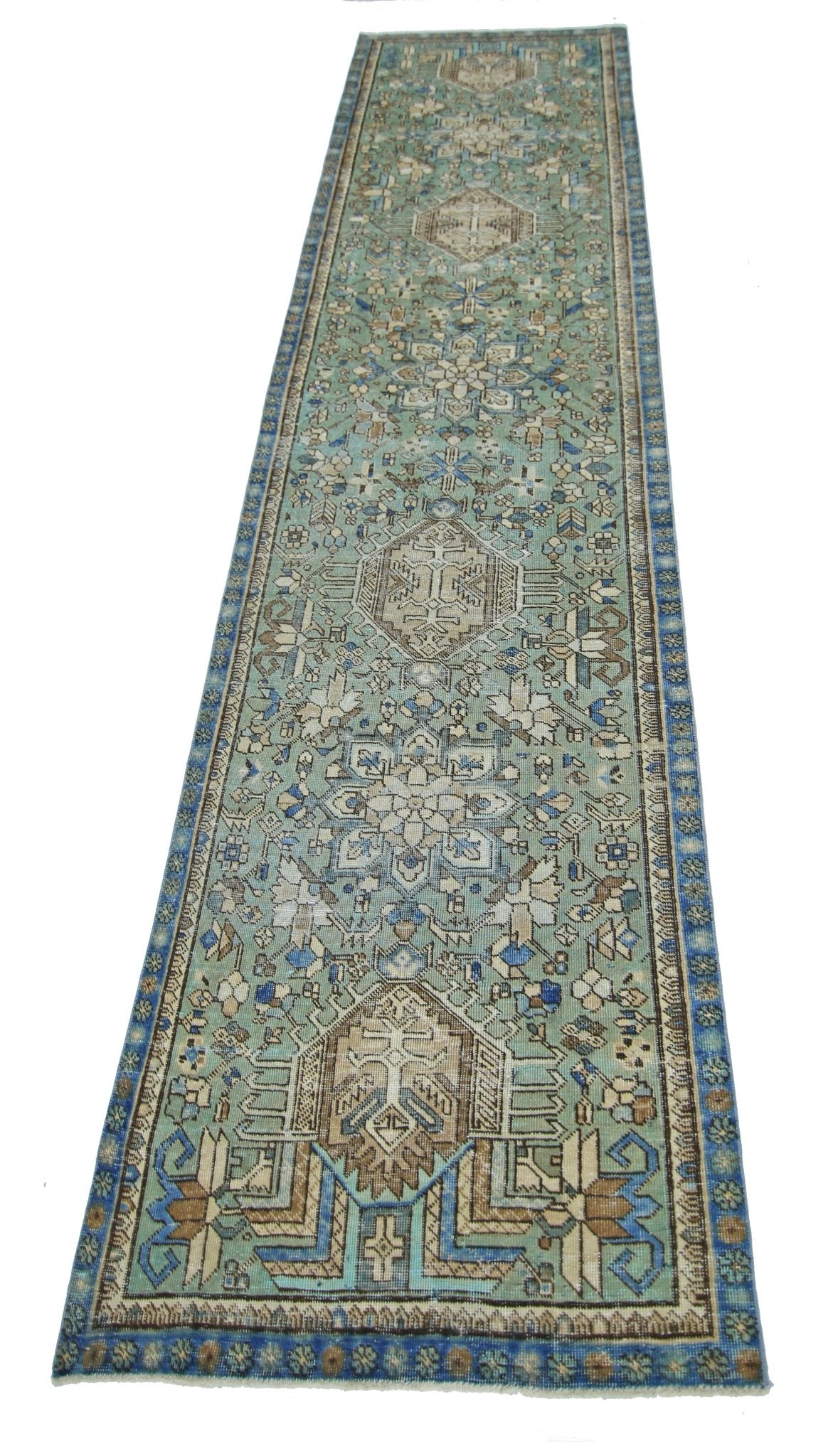 A long, handmade vintage Persian runner rug featuring intricate geometric patterns in shades of green.
