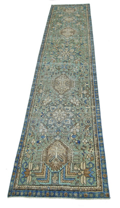 A long, handmade vintage Persian runner rug featuring intricate geometric patterns in shades of green.