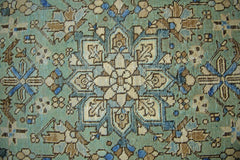 A vintage Persian runner featuring a detailed floral medallion pattern in blue and tan tones.
