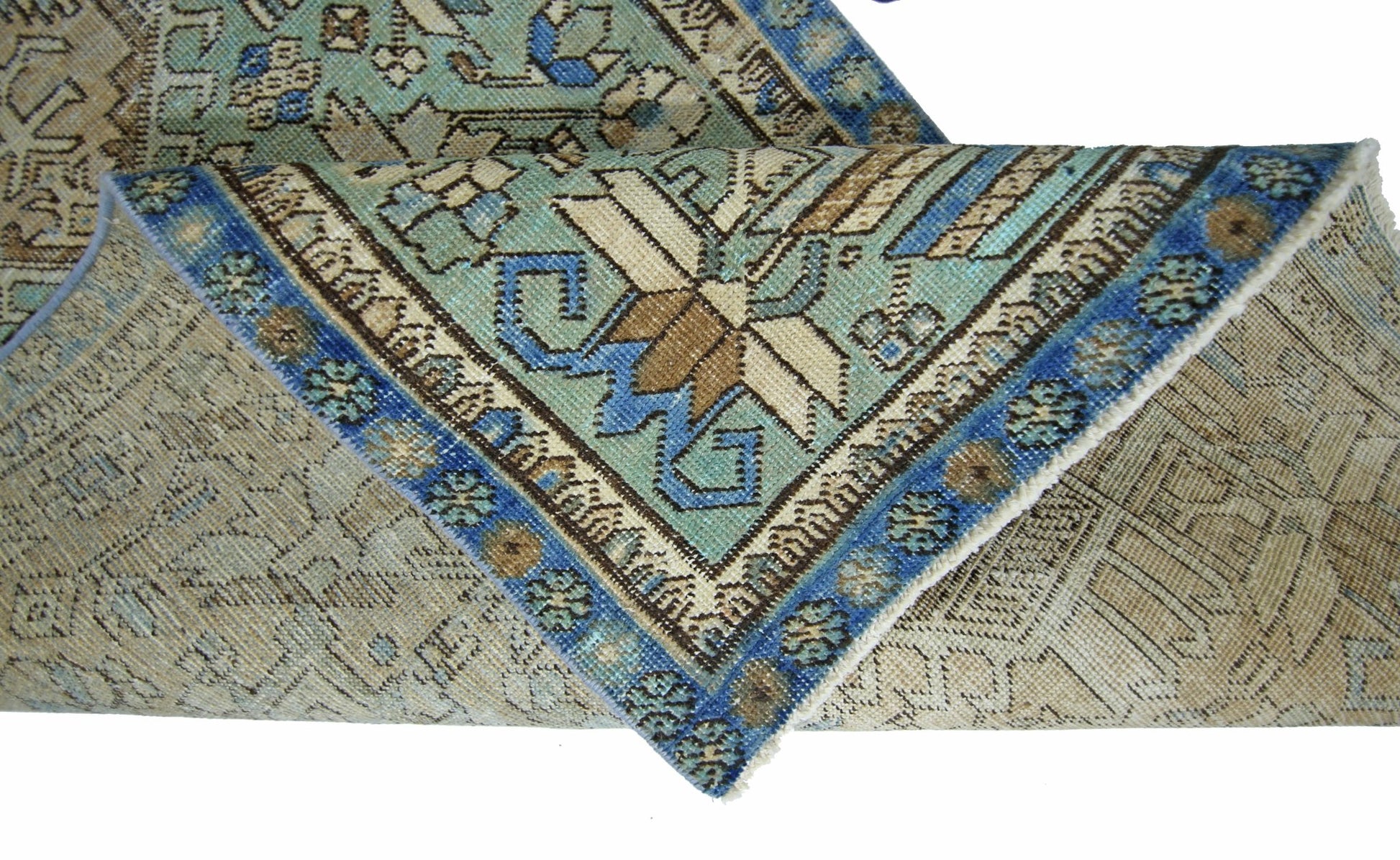 A folded vintage Persian runner featuring intricate geometric patterns in blue and beige tones.