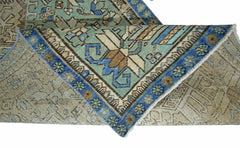 A folded vintage Persian runner featuring intricate geometric patterns in blue and beige tones.