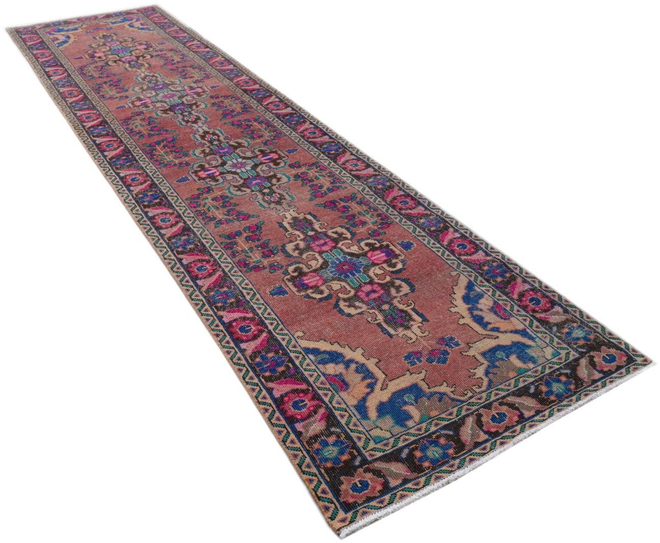 A vintage Persian runner rug featuring a faded red field with intricate floral and geometric motifs.