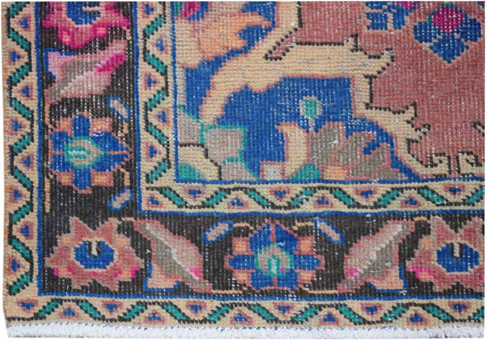 A close-up of a vintage Persian runner featuring a floral pattern in blue, pink, and tan.