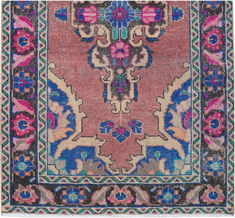 A vintage handmade Persian runner rug featuring a floral medallion pattern in pink and blue tones.