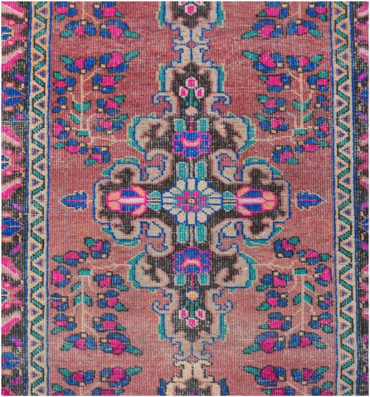 A vintage Persian runner featuring a central floral medallion on a dusty rose background.