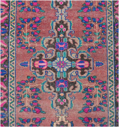 A vintage Persian runner featuring a central floral medallion on a dusty rose background.