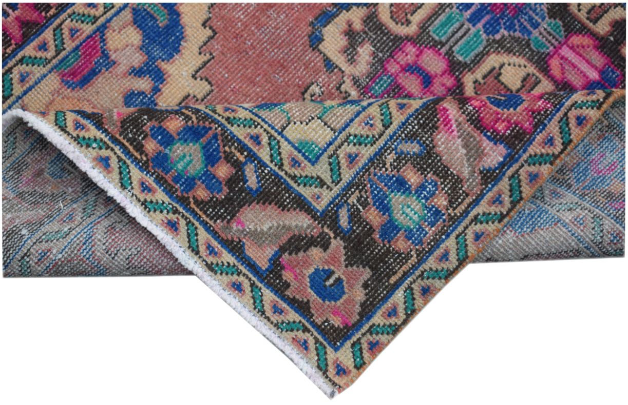 A folded vintage Persian runner featuring intricate floral patterns in blue, pink, and tan.