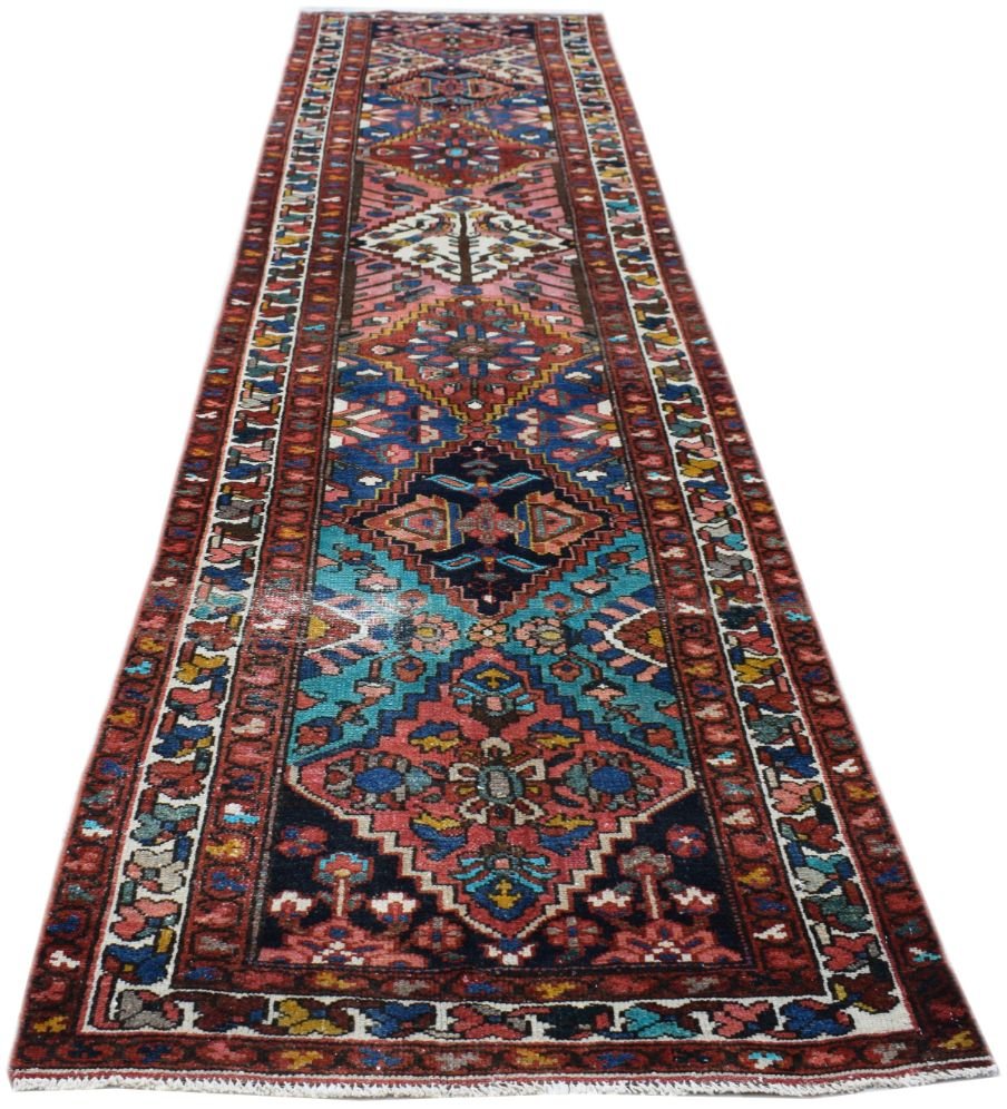A long, handmade vintage Persian runner rug featuring intricate geometric patterns in vibrant colors.