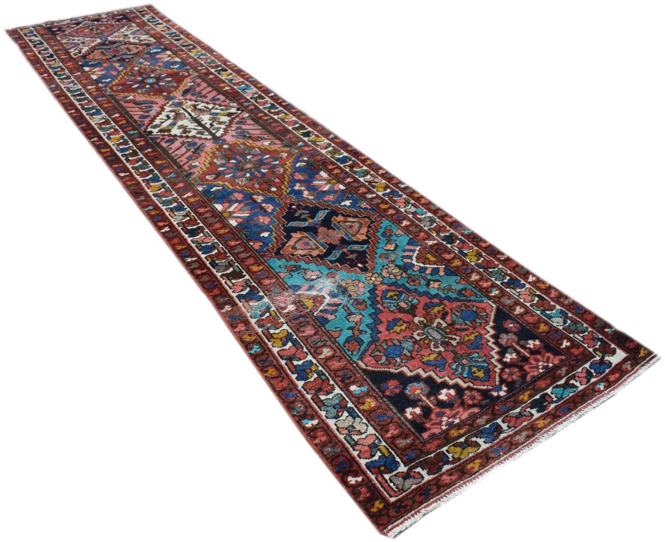 A handmade vintage Persian runner rug featuring intricate tribal patterns in blue and red tones.