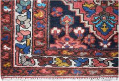 A vintage Persian runner featuring a dark blue field with geometric floral patterns and red borders.