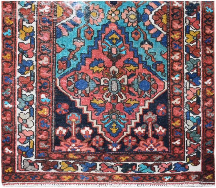 A vintage Persian runner featuring a central diamond medallion in red, blue, and teal wool.