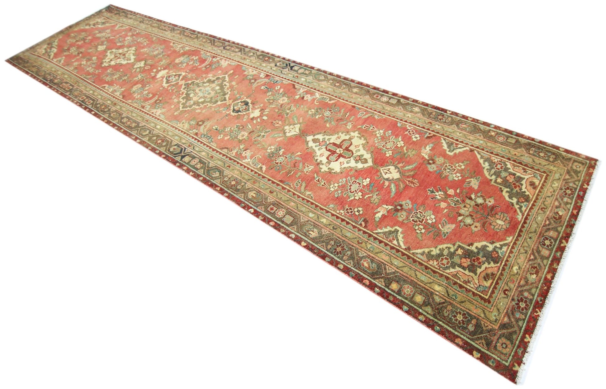 A vintage handmade Persian runner featuring a floral pattern in shades of red, green, and cream.