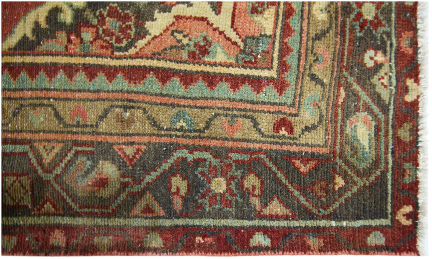 A close-up of a vintage Persian runner featuring intricate floral patterns in red, green, and tan.