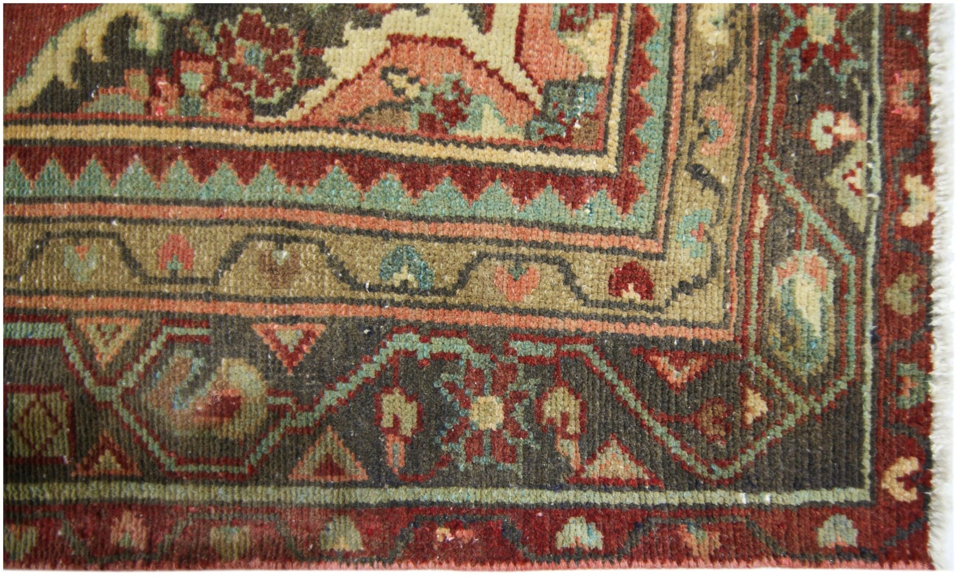 A close-up of a vintage Persian runner featuring intricate floral patterns in red, green, and tan.