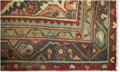 A close-up of a vintage Persian runner featuring intricate floral patterns in red, green, and tan.